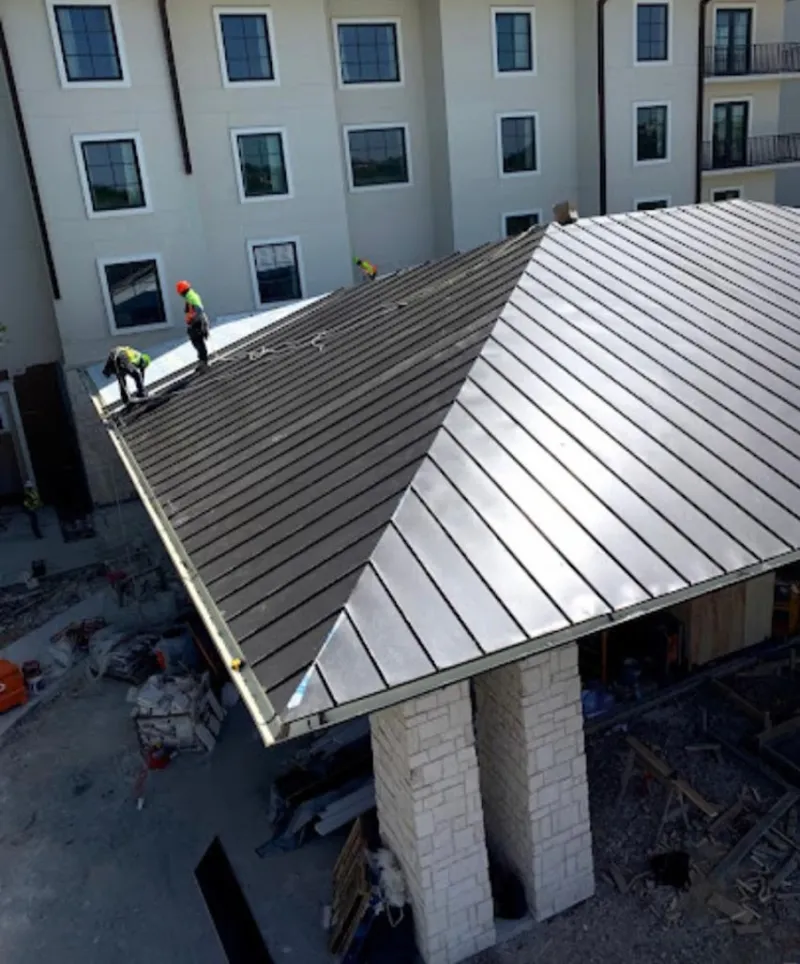 Crew installing standing seam metal roof panels on a commercial project in Oviedo